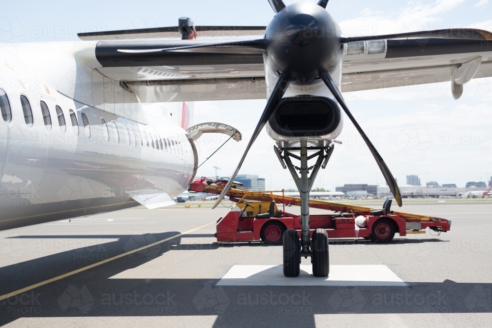 Luggage being loaded onto a plane with a propeller in foreground - Australian Stock Image