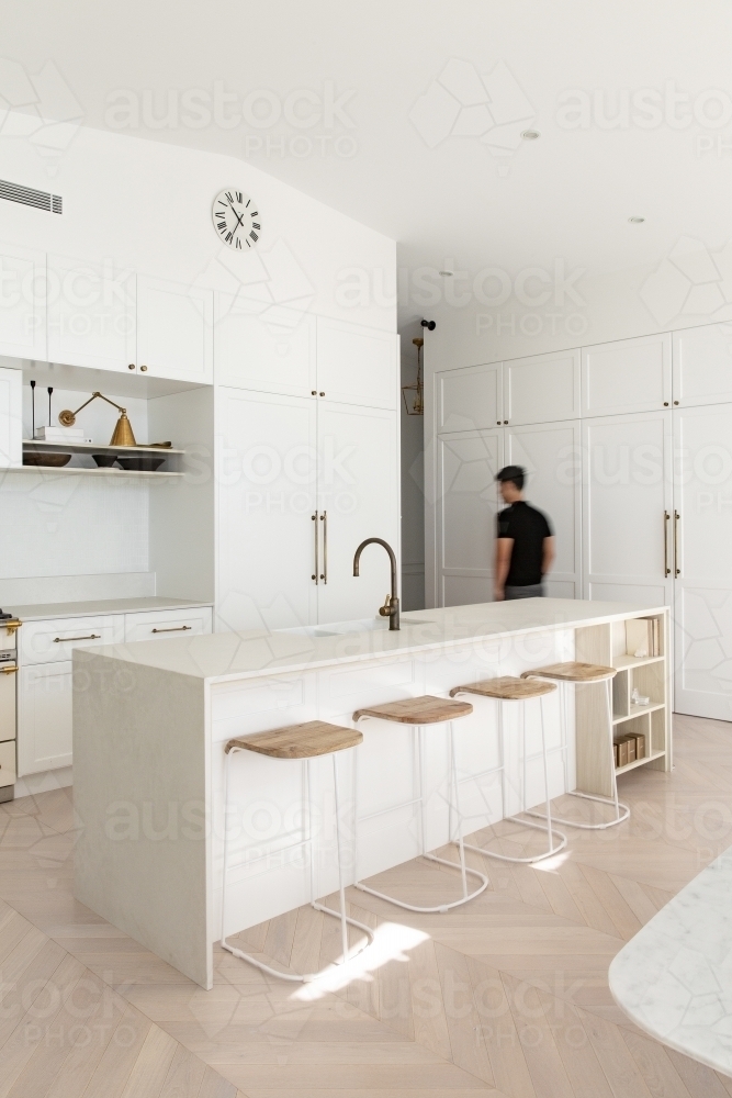 Luxurious high end designer white kitchen with a man walking past - Australian Stock Image