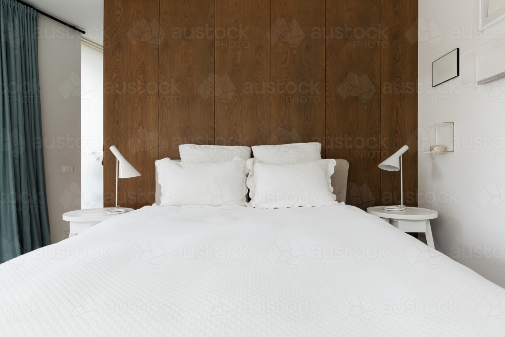 Luxury master bedroom with walnut wood panelling behind the bed - Australian Stock Image