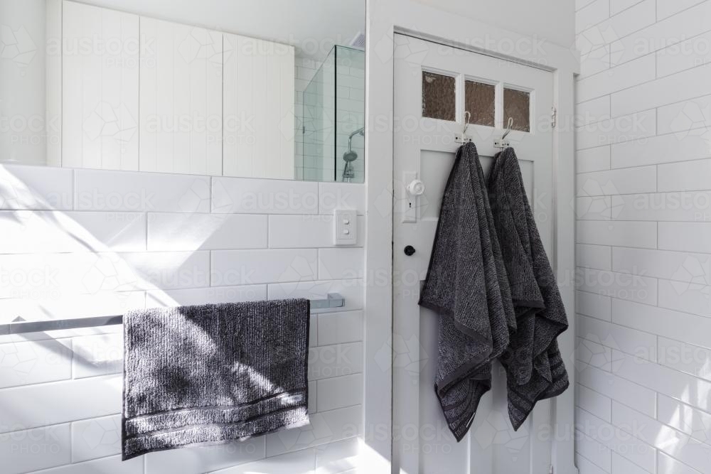 Luxury towels on door hooks in modern white bathroom with brick pattern subway tiles - Australian Stock Image