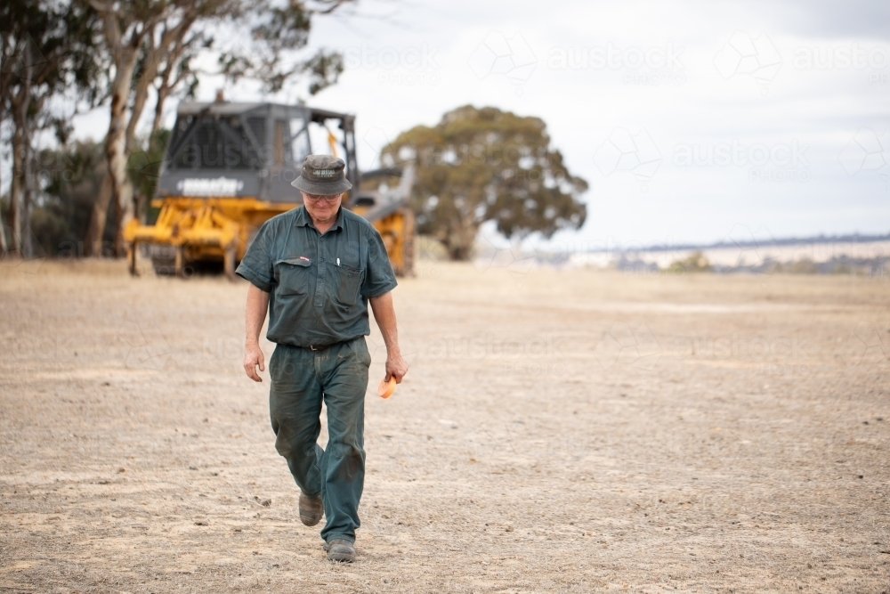 machine operator walking away from bulldozer - Australian Stock Image