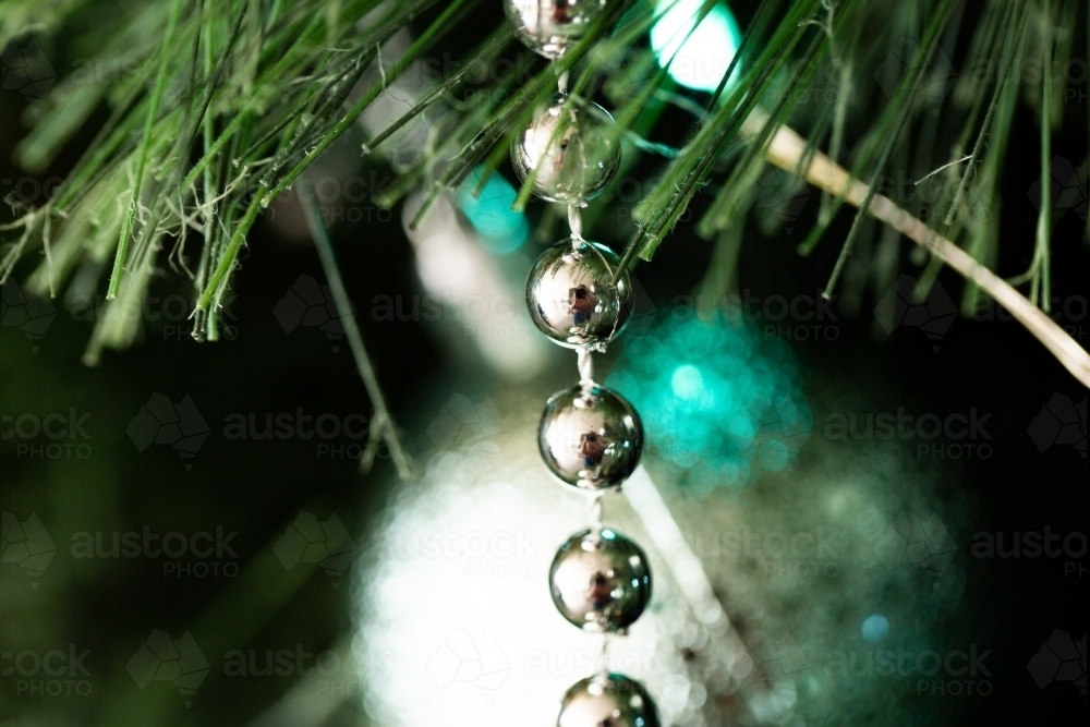 Macro close up shot of bauble with bead string hanging on plastic fir Christmas tree - Australian Stock Image