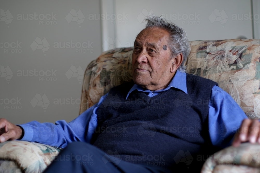 Male Aboriginal elder sitting in an armchair in his home - Australian Stock Image