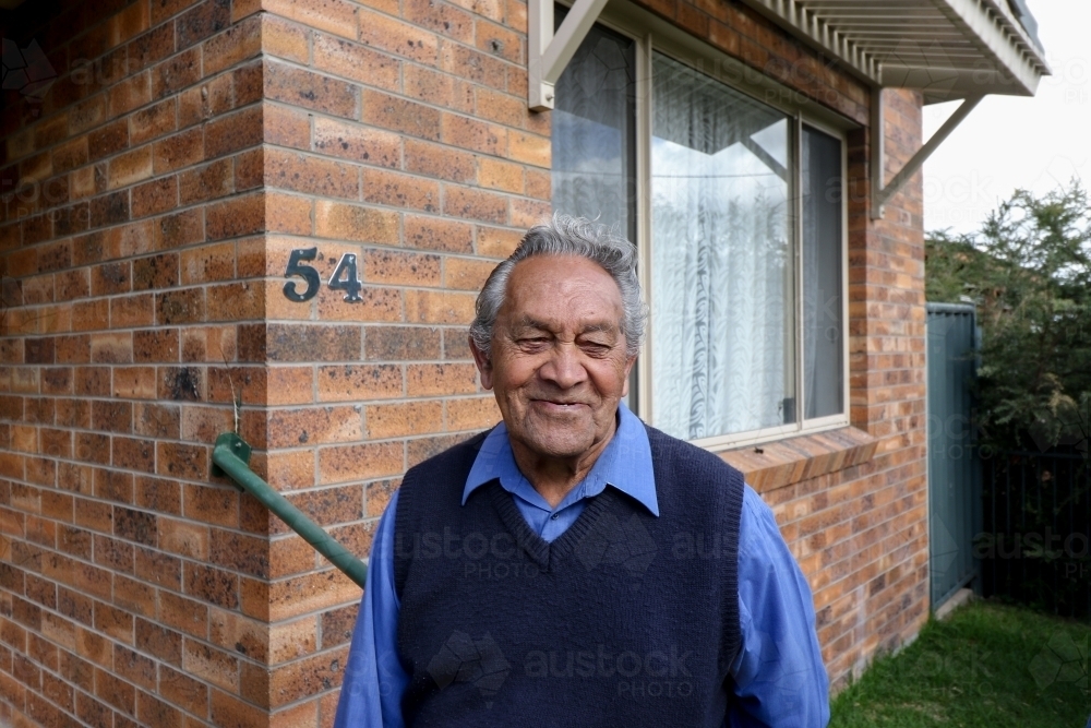 Male Aboriginal elder standing in front of his home - Australian Stock Image