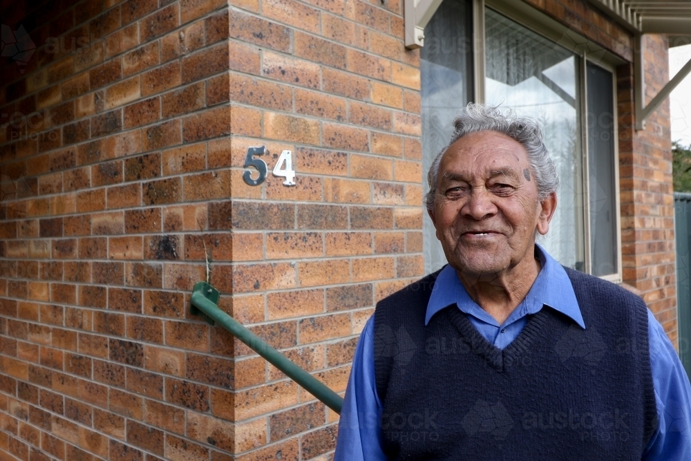 Male Aboriginal elder standing in front of his home - Australian Stock Image