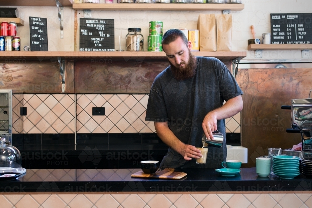 Male barista making coffee inside cafe - Australian Stock Image