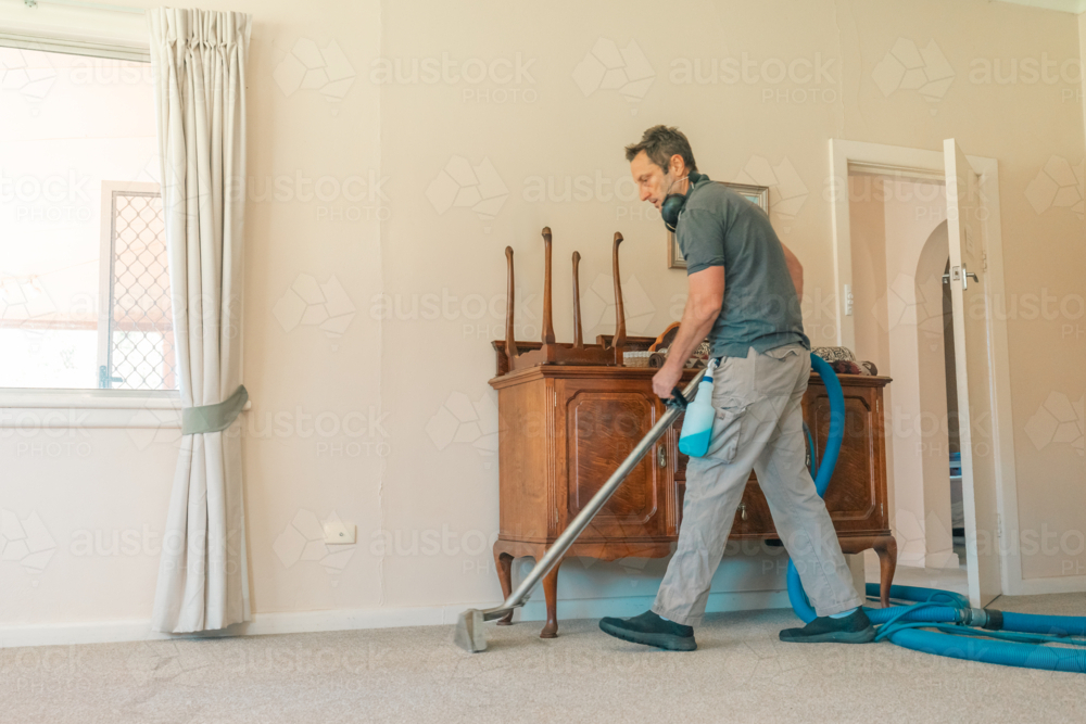 Image of Male carpet cleaning professional using steam cleaner in home ...