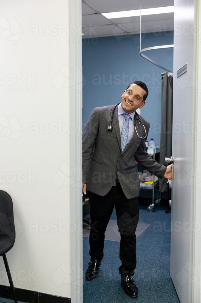 Male doctor opening clinic door - Australian Stock Image