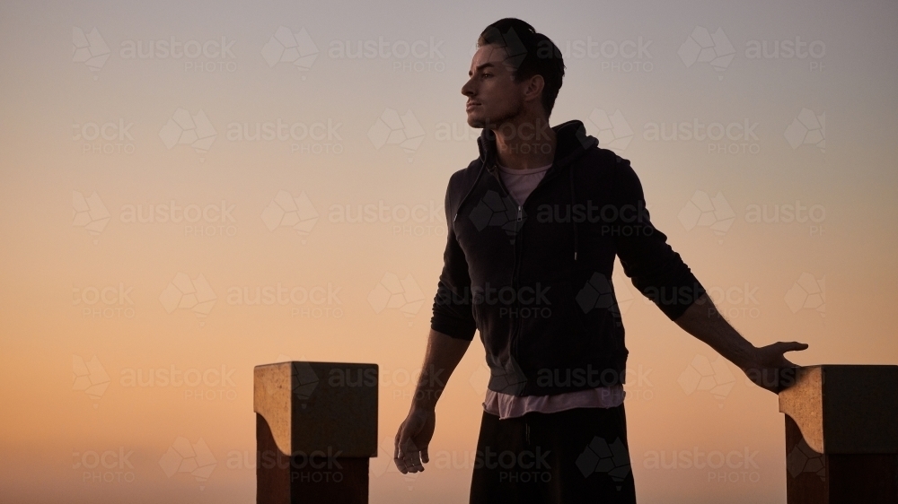 Male doing stretch exercise beside ocean - Australian Stock Image
