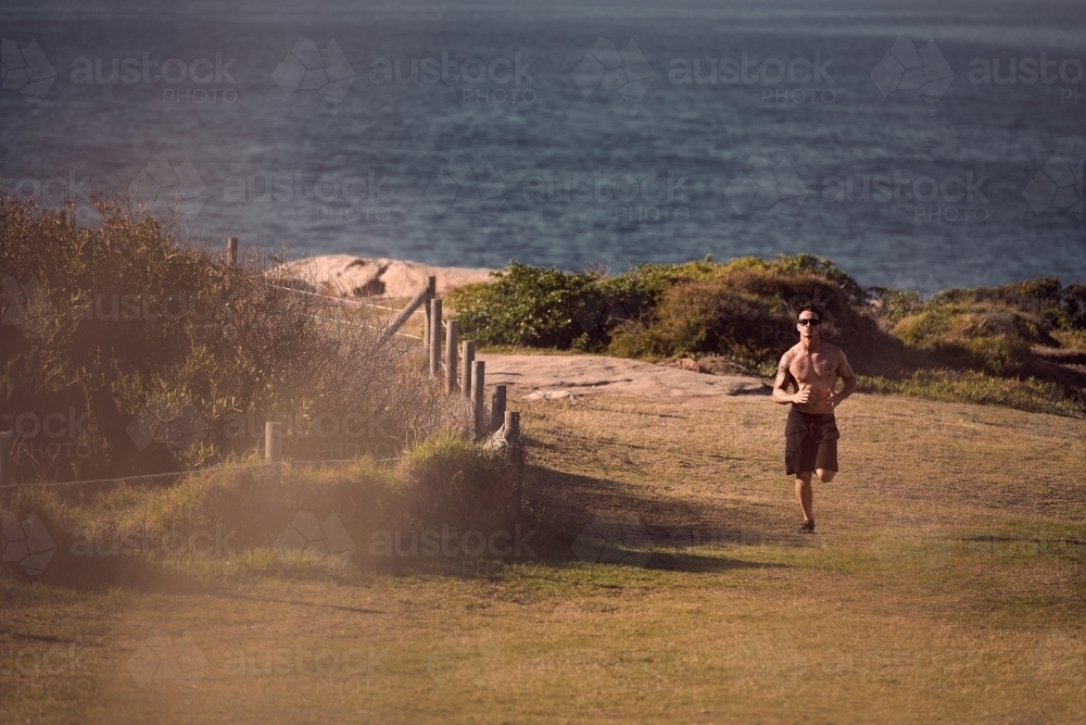 Male exercising on a morning run beside the ocean - Australian Stock Image