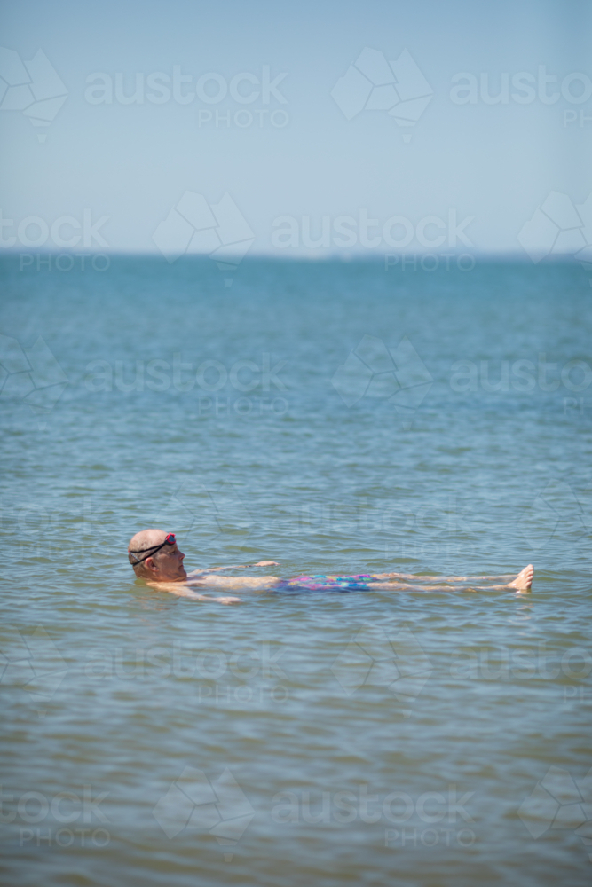 Male open water swimmer floating on back in water - Australian Stock Image