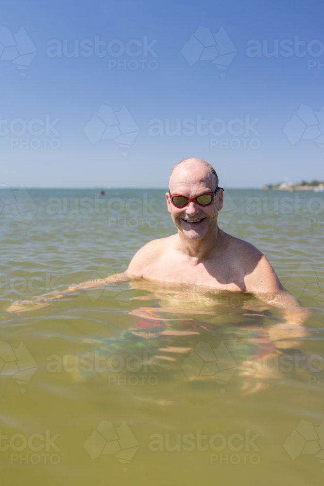 Male open water swimmer wearing goggles smiling in portrait - Australian Stock Image