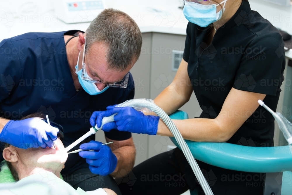Male patient having teeth cleaned at dentist - Australian Stock Image