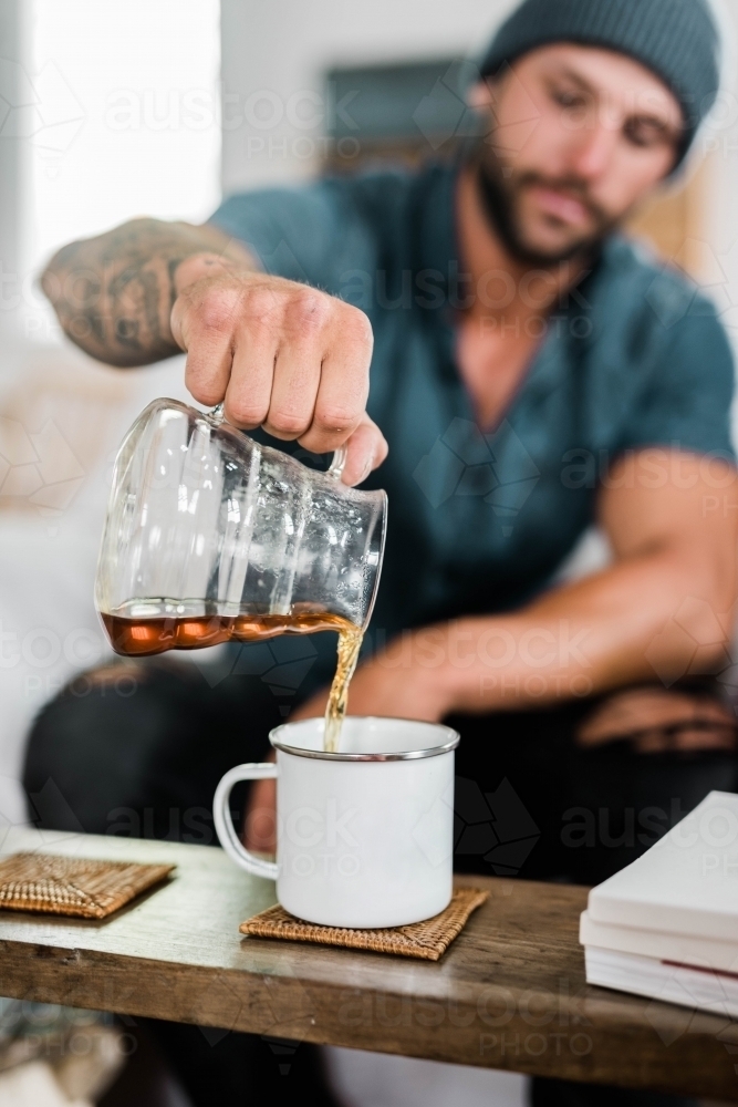 Male pouring coffee into a cup at home - Australian Stock Image
