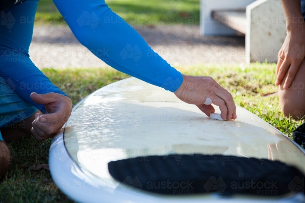 Male surfer waxing new surfboard with wax - Australian Stock Image