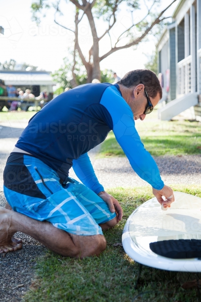 Male surfer waxing new surfboard with wax - Australian Stock Image