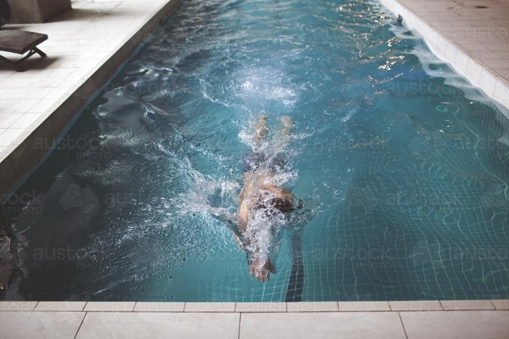 Male swimmer enjoying contemporary indoor lap pool - Australian Stock Image