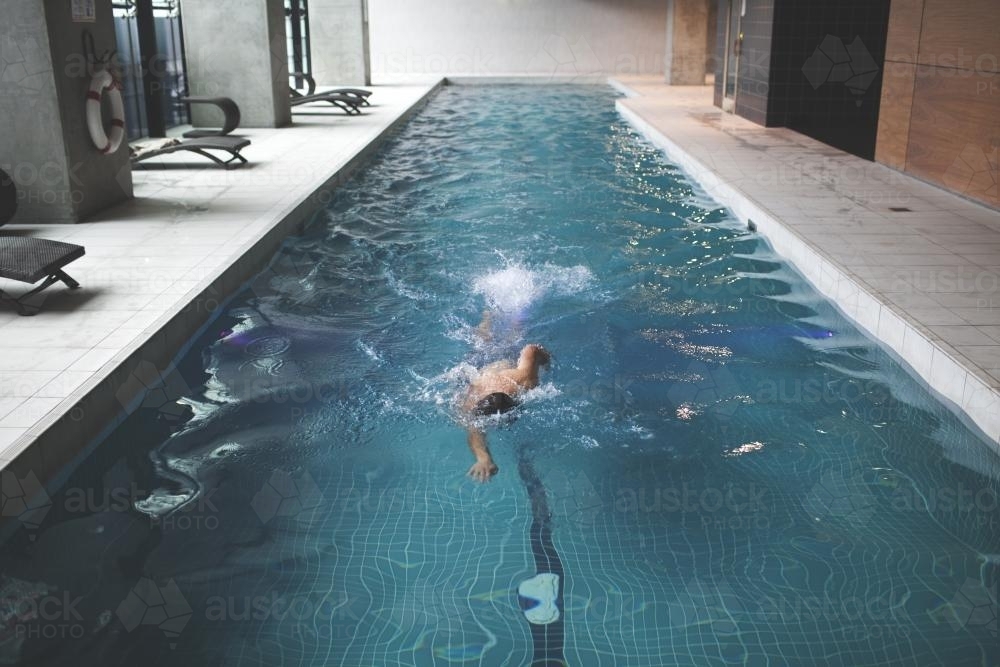 Male swimmer enjoying contemporary indoor lap pool - Australian Stock Image