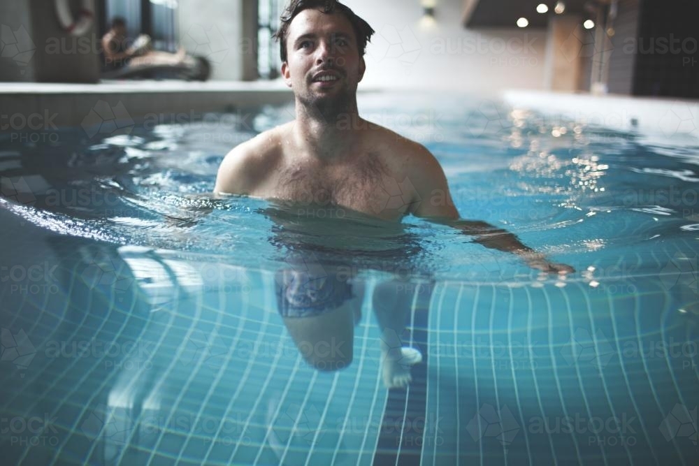 Male swimmer walking in contemporary indoor lap pool - Australian Stock Image