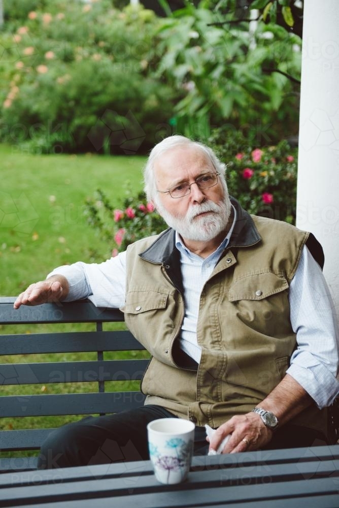 Male university teacher having a coffee break in the garden - Australian Stock Image