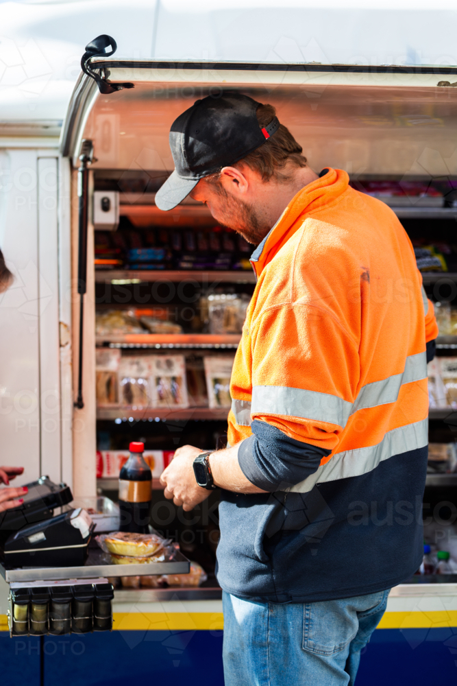male worker on lunch break at industrial workplace purchasing food - Australian Stock Image
