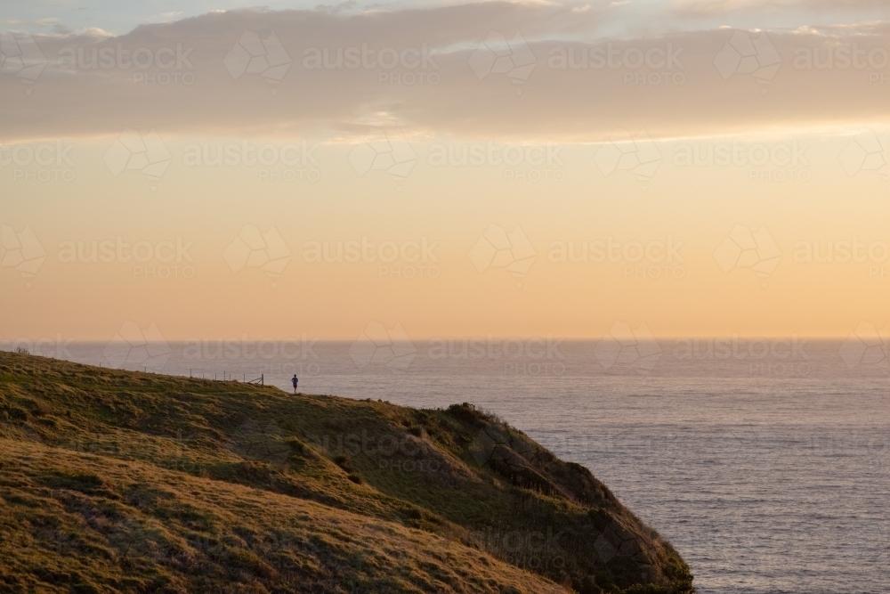 Man alone on cliff edge overlooking ocean - Australian Stock Image