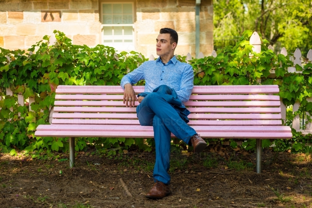 man alone on park bench in a park - Australian Stock Image