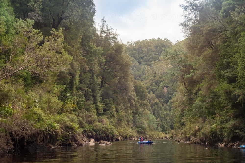 Man and child on kayak on river surrounded by forest - Australian Stock Image