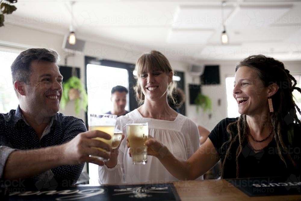 Man and two women raising glasses at local craft beer bar - Australian Stock Image