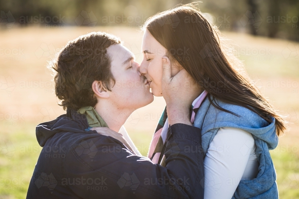Man and woman kissing with man holding woman's face - Australian Stock Image