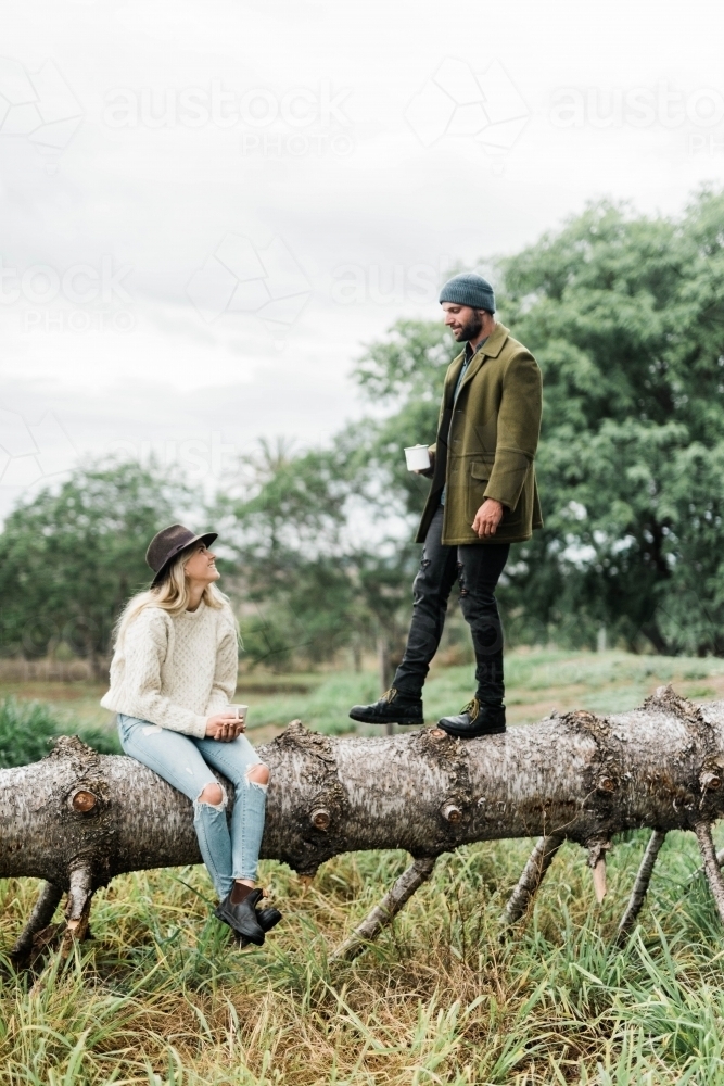 Man and woman on fallen tree on a rural property - Australian Stock Image