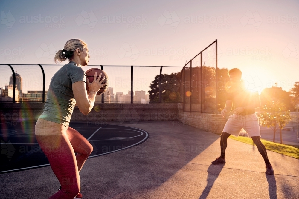 Man and woman passing basketball in sunlight - Australian Stock Image