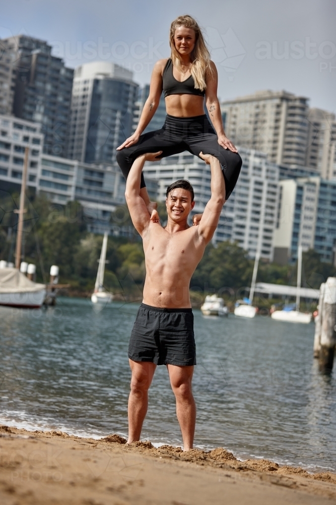 Man and woman practising acrobatics on beach - Australian Stock Image