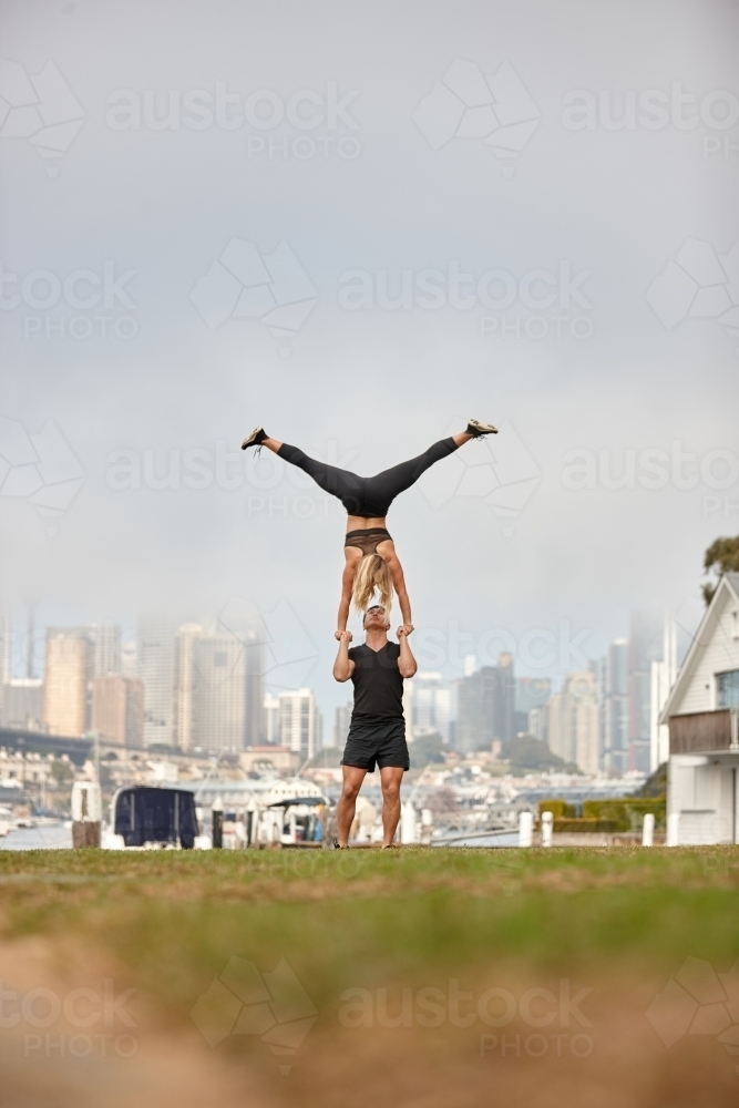 Man and woman practising acrobatics with city in background - Australian Stock Image