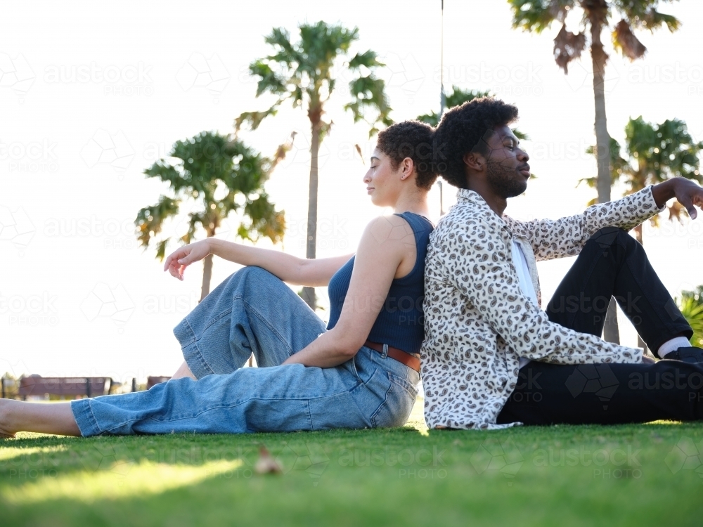 Image of Man and woman sitting backto back in park Austockphoto