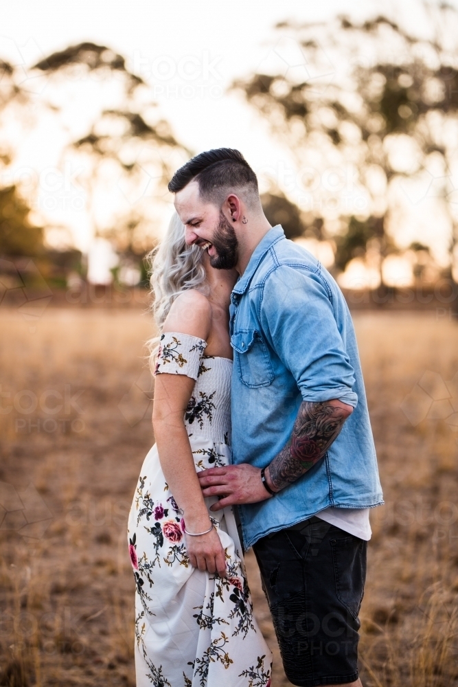 Man and woman standing together sharing secrets laughing - Australian Stock Image