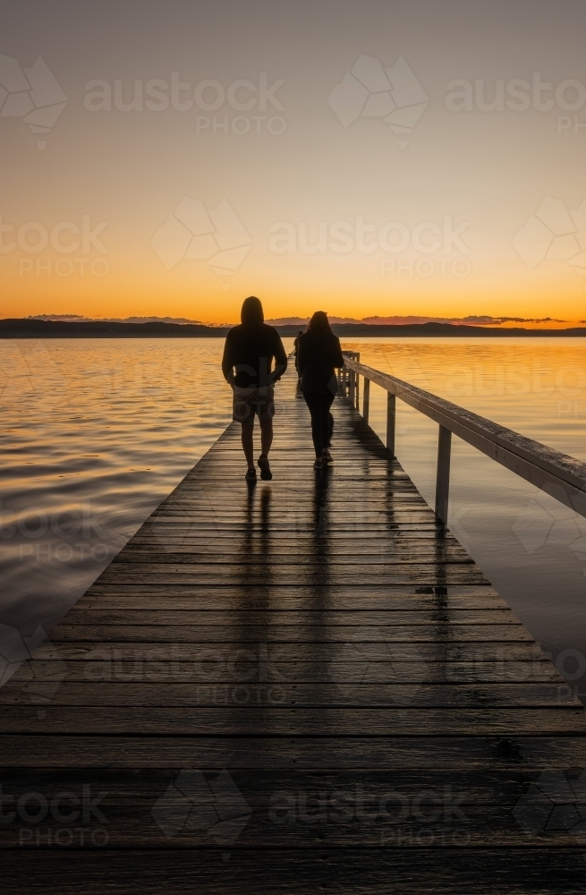 Man and Woman walking on Jetty at Sunset - Australian Stock Image