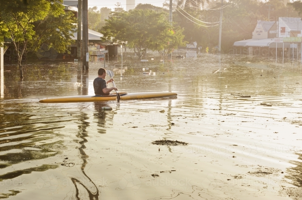 Man canoeing in flood waters - Australian Stock Image