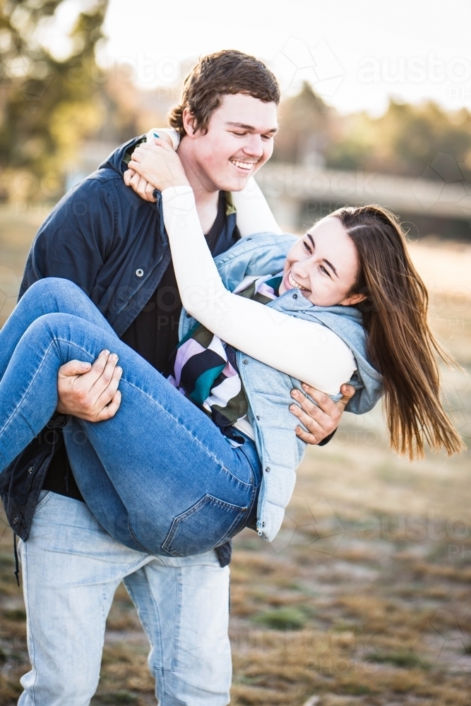Image of Man carrying girlfriend in his arms laughing 