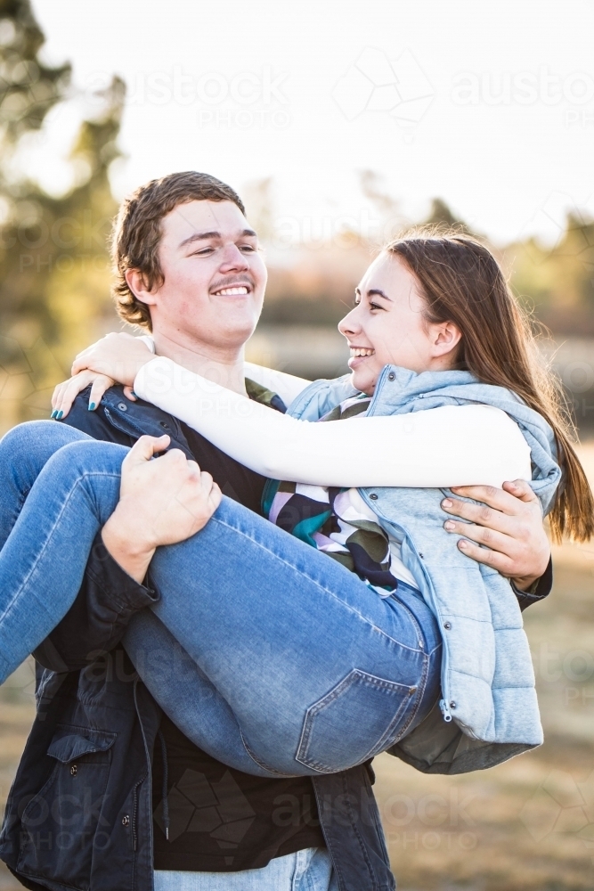 Man carrying girlfriend in his arms laughing - Australian Stock Image