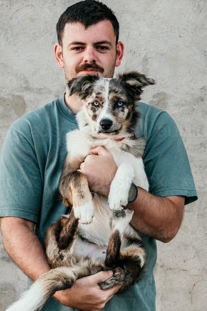 Man carrying his pet dog - Australian Stock Image