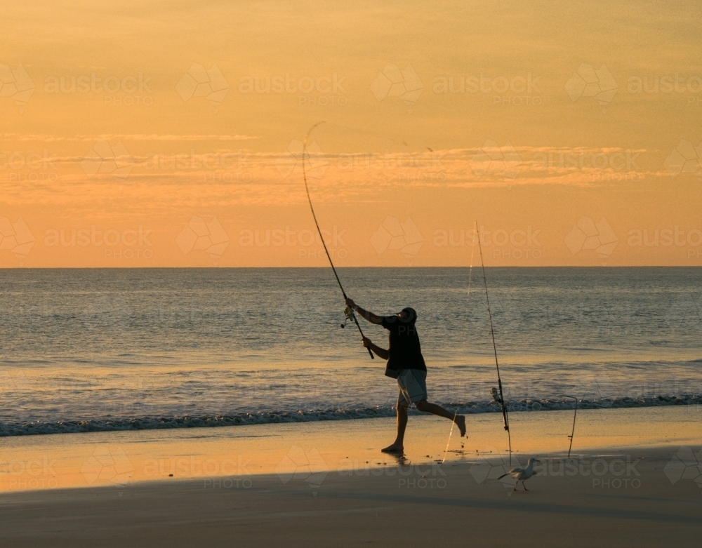 Man Casting a Surf Rod on Cable Beach at Dusk - Australian Stock Image