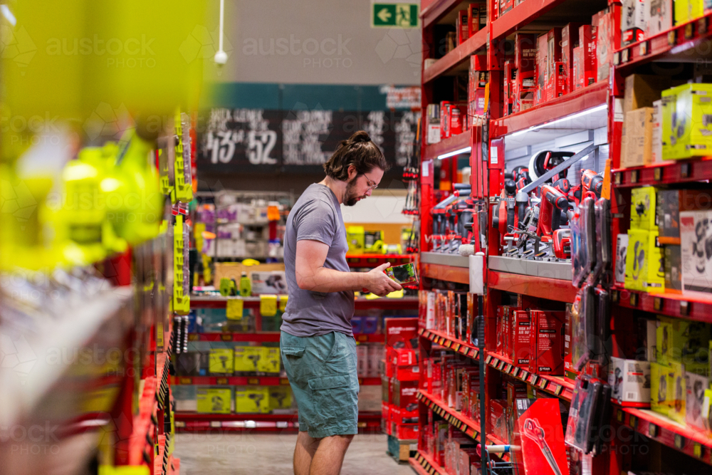 Man choosing product to purchase off shelf in hardware store shop - Australian Stock Image