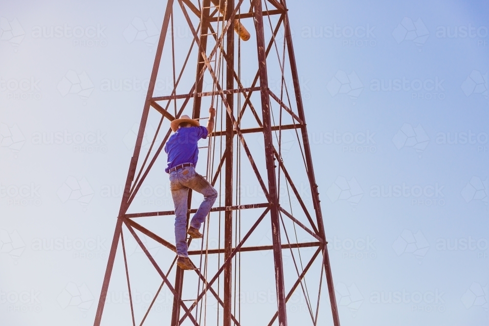 Man climbing windmill tower - Australian Stock Image