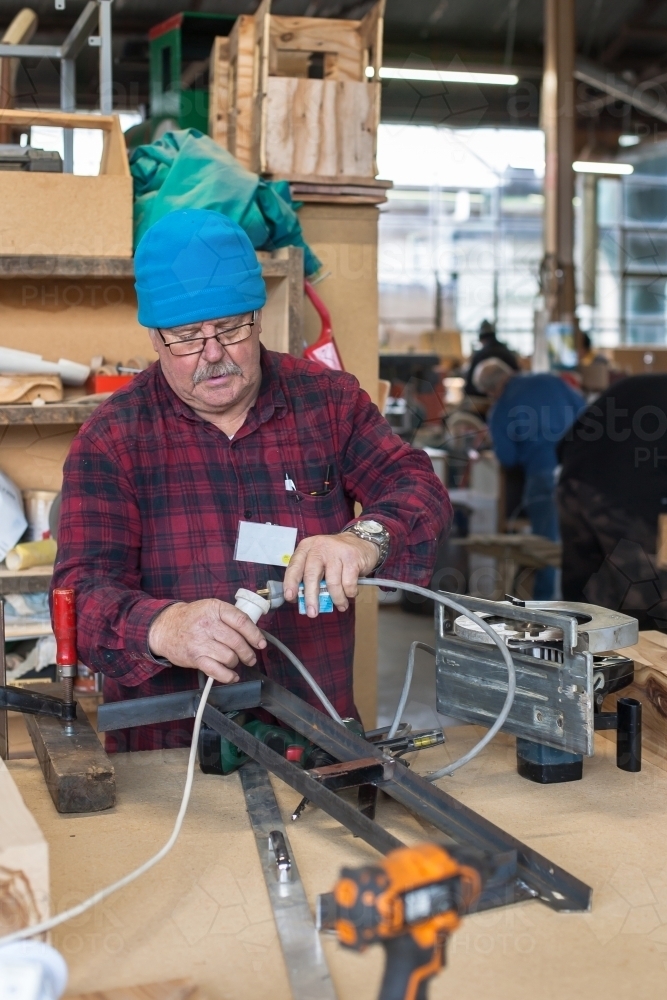 Man connecting power cord at a men's shed - Australian Stock Image