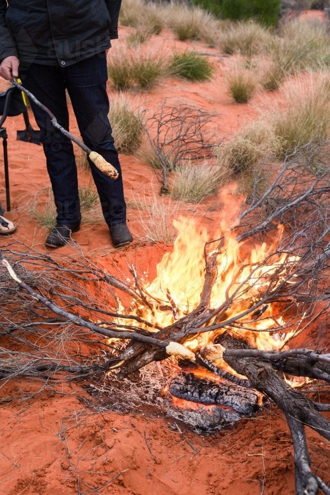 Man cooking damper over an open fire in Outback Australia - Australian Stock Image