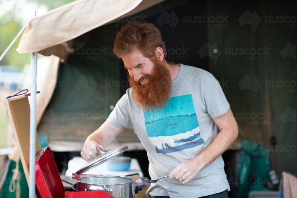 Man cooking on camp stove in camper trailer : Austockphoto Man cooking on camp stove in camper trailer - Australian Stock Image