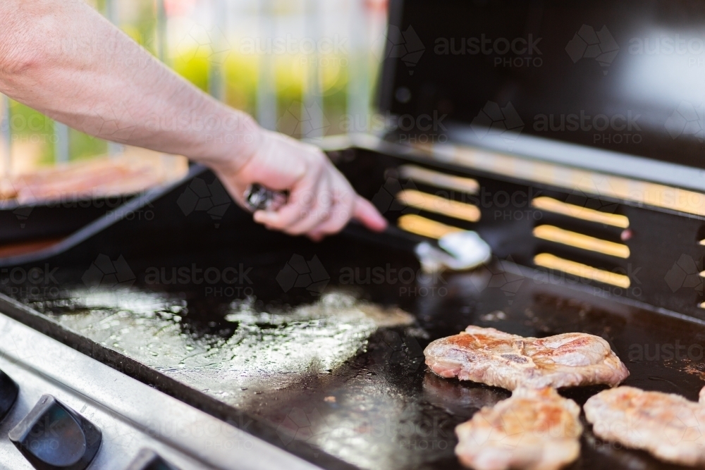 Man cooking steak in backyard bbq - Australian Stock Image