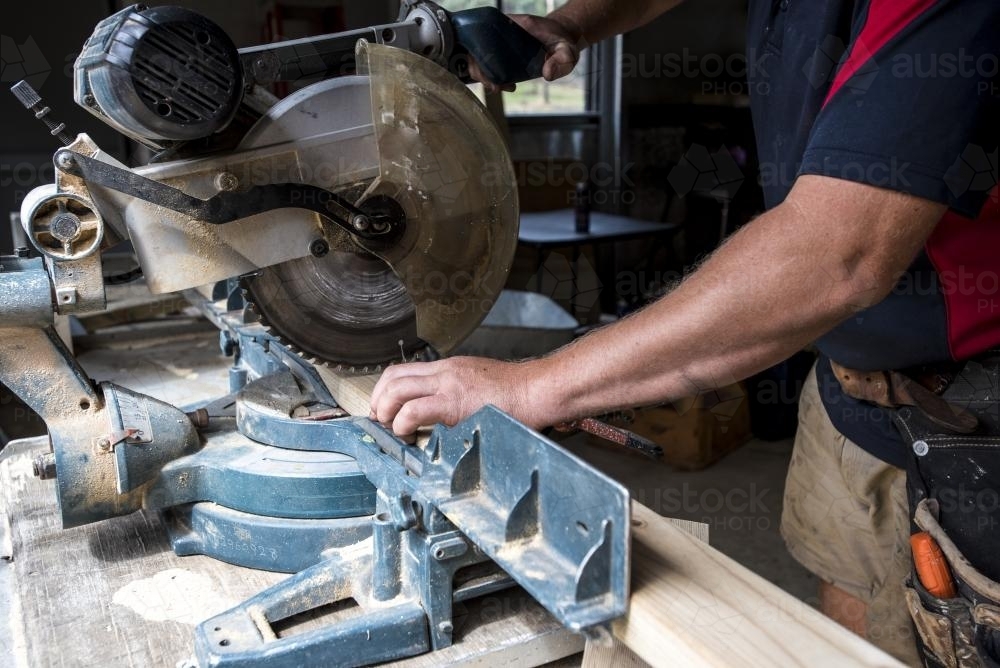 Image of Man cutting timber with drop saw Austockphoto