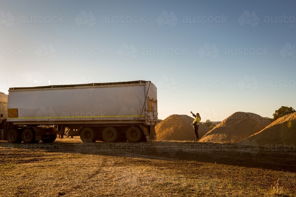 Man directing truck to piles of lime sand - Australian Stock Image